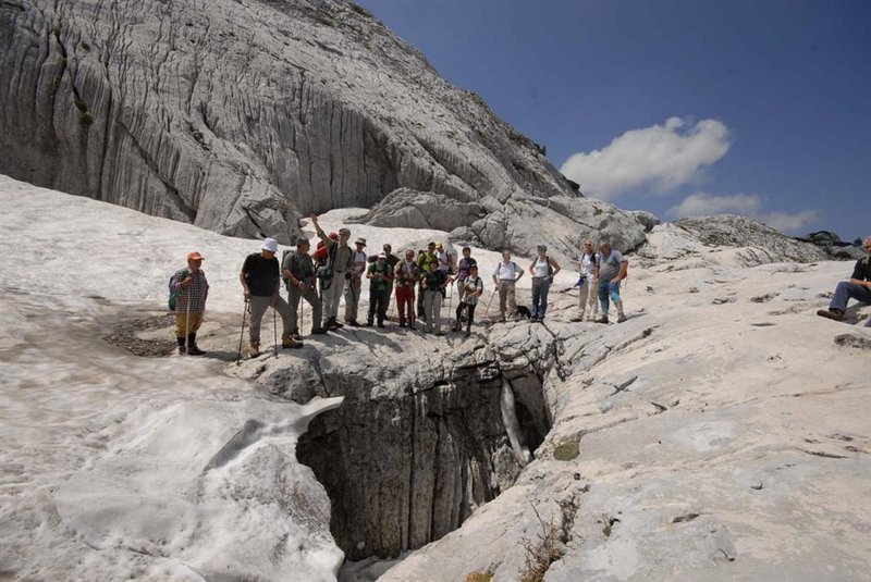 Escursionisti presso l'abisso Boegan sul sentiero geologico Foran Dal Mus, Altopiano del Monte Cani, Parco naturale delle Prealpi Giulie
